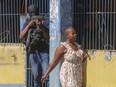 A resident of Port-au-Prince walks past a National Police officer guarding the empty National Penitentiary after a small fire inside the jail on Thursday.