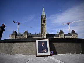 Members of Parliament are returning to the House of Commons today, where they're expected to offer tributes to Brian Mulroney. A person stands by the Centennial Flame near a framed portrait of former prime minister Brian Mulroney that was left there, following his death at the age of 84, in Ottawa, Friday, March 1, 2024.