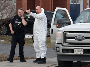 A police officer and a member of the coroner's office talk at the scene of a homicide where six people were found dead in the Barrhaven suburb of Ottawa on Thursday, March 7, 2024.