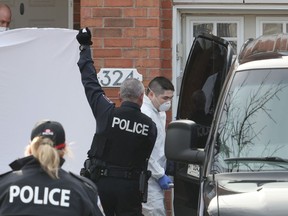 Police officers hold up a sheet as members of the coroner's office remove a body at the scene of a homicide where six people were found dead in the Barrhaven suburb of Ottawa on Thursday, March 7, 2024.