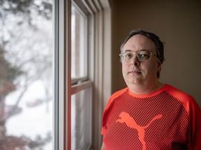 Man stands for a photograph in his apartment in Saskatoon