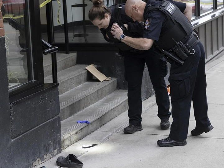  A Vancouver police investigator illuminates a knife on the sidewalk outside the Fairleigh Dickinson University in Vancouver, B.C. on March 20, 2024, the scene of a serious assault that took place approximately an hour earlier.