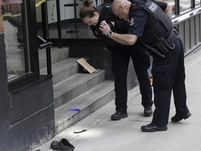 A Vancouver police investigator illuminates a knife on the sidewalk outside the Fairleigh Dickinson University in Vancouver, B.C. on March 20, 2024, the scene of a serious assault that took place approximately an hour earlier.