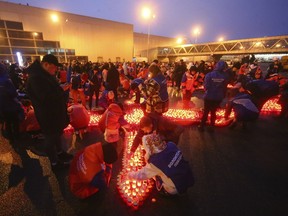 People light candles and lay flowers at a makeshift memorial in front of the Crocus City Hall on the western outskirts of Moscow, Russia, on Sunday, March 24, 2024. There were calls Monday for harsh punishment for those behind the attack on the Russia concert hall that killed more than 130 people as authorities combed the burnt-out ruins of the shopping and entertainment complex in search of more bodies.
