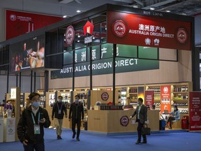 FILE - Visitors wearing face masks walk past a display of Australian wines and other agricultural products at the China International Import Expo (CIIE) in Shanghai, China, Nov. 5, 2020. China on Thursday, March 28, 2024, said it would lift tariffs placed on Australian wine over three years ago, in a sign of improving ties between Australia and China.