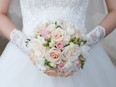 Cream wedding bouquet of roses and freesias in the hands of the bride