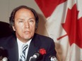 Canadian Prime Minister Pierre Elliott Trudeau, wearing a rose in his buttonhole, addresses media 23 October 1974 in Paris in front of a Canadian flag.