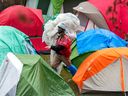 An anti-Israel demonstrator carries tarps through the encampment on the campus of McGill University in Montreal Tuesday April 30, 2024.