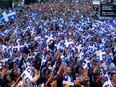 A huge crowd waves Quebec flags and cheers.