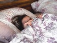 woman hides face under covers