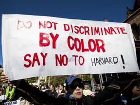 A demonstrator against Harvard University's admission process holds a sign that reads "Do Not Discriminate By Color Say No To Harvard" during a protest at Copley Square in Boston, Massachusetts, U.S., on Sunday, Oct. 14, 2018. Harvard University was sued by a group that claims their law school illegally used race and gender as criteria for selecting law students to staff their most elite academic journals, a suit that comes amid growing scrutiny of affirmative action in college admissions.