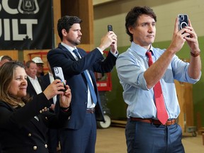 Justin Trudeau and two ministers staring at their phones.