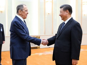 Sergei Lavrov and Xi Jinping shake hands.