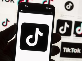 The TikTok logo is seen on a mobile phone in front of a computer screen which displays the TikTok home screen, Oct. 14, 2022, in Boston.