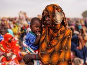 A closeup of a woman and young child in a crowd of refugees.