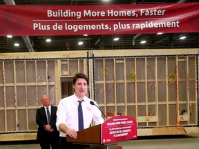 Trudeau standing under a housing banner