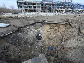 A worker sits in a crater after a Russian missile strike on Kharkiv, Ukraine.