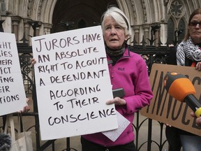 Protester Trudi Warner holding a sign outside the Royal Courts of Justice in London, following a High Court ruling in London, Monday, April 22, 2024. A London judge says a climate protester who could have faced up to two years in prison for holding a sign outside a courthouse reminding jurors of their right to acquit defendants should not be charged with contempt of court. High Court Justice Pushpinder Saini said Monday that Trudi Warner's act was not a crime because jurors can reach a verdict based on their conscience.