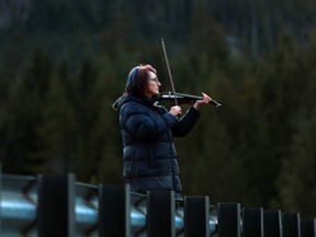 Carol Love plays "Tennessee Whiskey" on her violin at a todal lagoon near Zeballos, B.C., on Wednesday, April 17, 2024. The Nanaimo, B.C., woman says she is serenading a killer whale calf, hoping to entice the orca to leave the remote lagoon where she has been trapped alone for almost four weeks.
