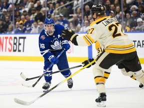 Toronto Maple Leafs right wing Mitchell Marner (16) passes the puck past Boston Bruins centre Matthew Poitras (51) and defenceman Hampus Lindholm (27) during first period NHL hockey action in Toronto on Saturday, Dec. 2, 2023.