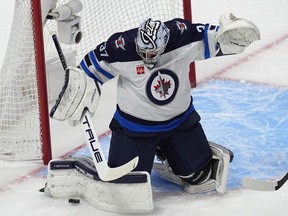 Winnipeg Jets goaltender Connor Hellebuyck makes a pad-save in the first period of Game 4 of an NHL Stanley Cup first-round playoff series against the Colorado Avalanche, Sunday, April 28, 2024, in Denver.