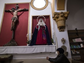 FILE - A woman prays at the San Ramon Nonato church after an Easter Holy Week procession was cancelled due to the coronavirus outbreak in Madrid, Spain, Thursday, April 9, 2020. Spain has approved a plan aimed at making reparation and economic compensation for victims of sex abuses committed by people connected to the Catholic Church.