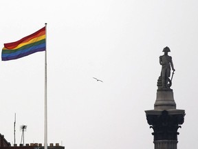 FILE - The rainbow flag, a symbol of the LGBTQ+ community, flies over a building next to Nelson's Column monument, right, in Trafalgar Square, central London, Britain, March 28, 2014. Children who question their gender identity are being let down by lack of evidence and a toxic political debate, according to a report Wednesday from a senior doctor in in England.