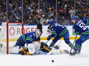 Nashville Predators' Jeremy Lauzon, front left, collides with Vancouver Canucks goalie Thatcher Demko (35) as Phillip Di Giuseppe (34) and Teddy Blueger (53) defend during the second period in Game 1 of an NHL hockey Stanley Cup first-round playoff series, in Vancouver, on Sunday, April 21, 2024.