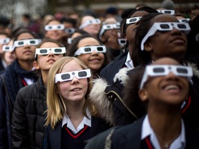 Children with protective glasses watch an eclipse.