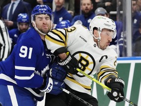 Toronto Maple Leafs' John Tavares (91) takes an elbow from Boston Bruins' Brad Marchand (63) during first period action in Game 4 of an NHL hockey Stanley Cup first-round playoff series in Toronto on Saturday, April 27, 2024.