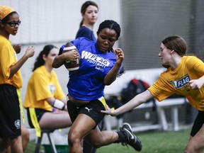 Elyssa Cadieux, a grade 9 student from CSLR high school reaches for Solape Obasa's flag, a grade 11 student in Elmwood High School, during a Blue Bombers High School Girls Flag Football League game in Winnipeg, Wednesday, April 10, 2024. Flag football organizations are hoping to see an influx of athletes as the sport will be introduced in the next olympic games.