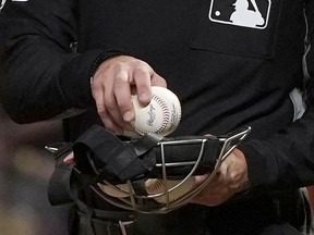 FILE - An umpire puts a ball into his face mask during a Major League Baseball game in San Francisco, Tuesday, June 15, 2021. A fired minor league umpire sued Major League Baseball, Wednesday, April 24, 2024, claiming he was sexually harassed by a female umpire and discriminated against because he is male and bisexual.