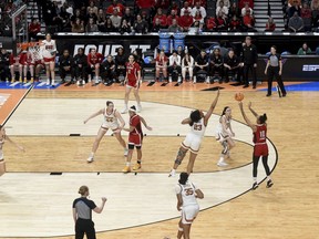 North Carolina State guard Aziaha James (10) shoots the ball over Texas forward Aaliyah Moore (23) as guard Shaylee Gonzales, center looks on from the three-point line during the second half of a Elite Eight college basketball game in the NCAA Tournament, Sunday, March 31, 2024, in Portland, Ore.
