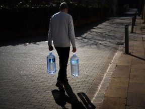 FILE - Joan Torrent, 64, walks toward his house carrying two plastic jugs of water refilled at a natural spring in Gualba, about 50 km, (31 miles) northwest of Barcelona, Spain, Wednesday, Jan 31, 2024. Spain's drought-stricken northeastern Catalonia is considering imposing water restrictions on tourists in the driest parts of the region if domestic consumption is not curtailed, the Catalan government said Tuesday April 16, 2024.