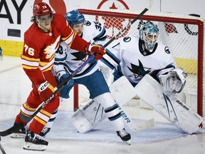 San Jose Sharks defenceman Calen Addison (33) checks Calgary Flames forward Martin Pospisil (76) as goalie Devin Cooley (1) follows the play during second period NHL hockey action in Calgary, Thursday, April 18, 2024. Winning more games and the construction of a new arena will convince more NHL players that Calgary is a desirable place to play, some Flames say as they head for the exits.THE CANADIAN PRESS/Jeff McIntosh