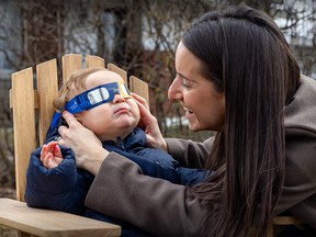 Emilie Alepin tries a pair of eclipse glasses on her 11-month-old son Leo Bartolone.