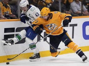 Vancouver Canucks defenseman Quinn Hughes (43) and Nashville Predators right wing Luke Evangelista (77) battle for the puck during the second period in Game 3 of an NHL hockey Stanley Cup first-round playoff series Friday, April 26, 2024, in Nashville, Tenn.