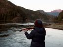 Carol Love plays her violin in an area where a pregnant orca died over three weeks ago in an effort to try and lure a two-year-old orca calf out of a lagoon she's been living in for over three weeks at Zeballos, B.C., on April 17, 2024.