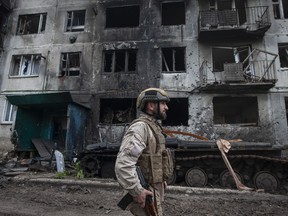FILE - A Ukrainian soldier passes by a damaged apartment building in Chasiv Yar, the site of heavy battles with the Russian forces in the Donetsk region, Ukraine, Tuesday, May 9, 2023.