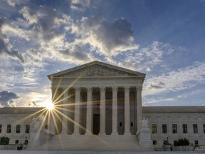 FILE - The sun flares in the camera lens as it rises behind the U.S. Supreme Court building in Washington, June 25, 2017. The Supreme Court will hear an appeal from a Vista, Calif., CBD hemp oil company fighting a lawsuit from a truck driver who says he got fired after using a product falsely advertised as being free from the active ingredient in marijuana.