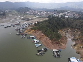 FILE - Boats sit docked around the exposed banks of the El Penol-Guatape hydroelectric dam, due to low water levels, in Guatape, Colombia, April 3, 2024. Colombia's government on Tuesday, April 23, 2024, rolled out new incentives to reduce electricity consumption in the South American nation, which has been hit by a severe drought that has diminished the capacity of local hydroelectric plants and brought officials close to imposing power cuts.