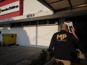 An agent from the Attorney General's office enters Save the Children's headquarters during a raid, in Guatemala City, Thursday, April 25, 2024. The NGO is being investigated for an alleged complaint about the violation of migrant children's rights, according to statements made by prosecutor Rafel Curruchiche.