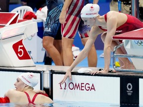 Canada's Summer McIntosh, right, reaches out to teammate Penny Oleksiak at the end of the women's 4x200m swimming final event during the Tokyo Summer Olympic Games.