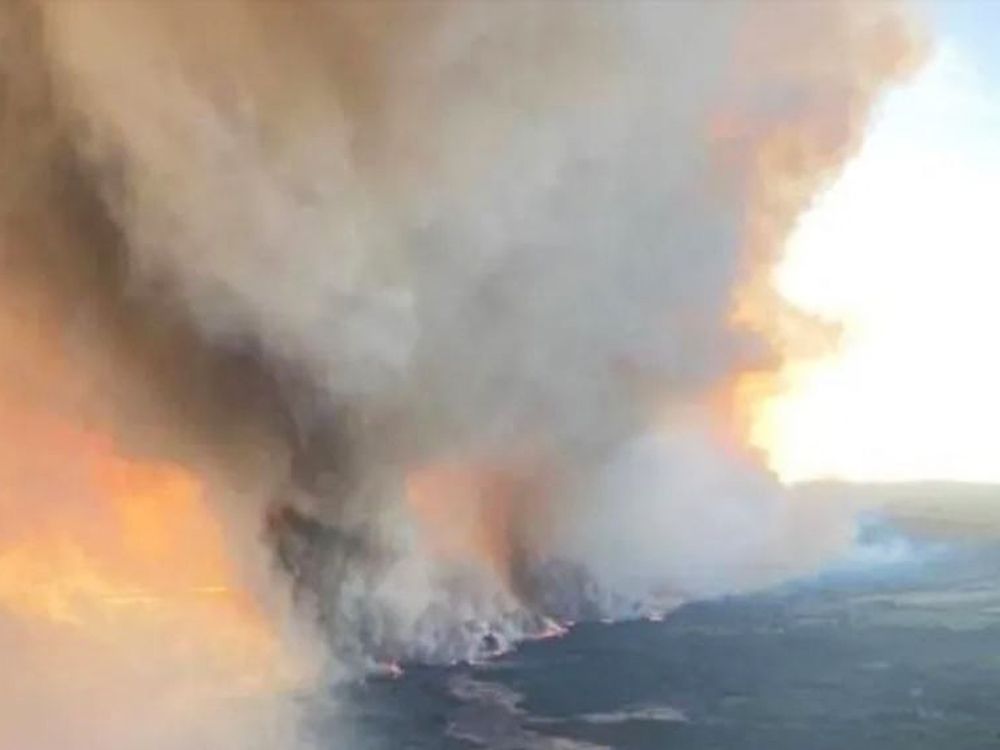 A wildfire burning near Fort Nelson, British Columbia, is seen through an airplane window on May 10, 2024.