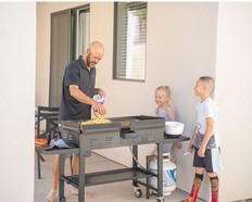Kids gathered while a man cooks on a Blackstone griddle