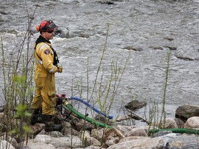 A firefighter monitors a pump in a river bed used for wildfire sprinklers in the evacuated neighbourhood of Grayling Terrace in Fort McMurray, Alta., Thursday, May 16, 2024.THE CANADIAN PRESS/Jeff McIntosh