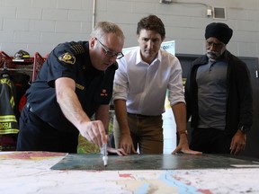 Prime Minister Justin Trudeau and Minister of Emergency Preparedness Harjit Sajjan meet with West Kelowna Fire Rescue Chief Jason Brolund to go over wildfire mapping at the fire hall in West Kelowna, B.C., Friday, May 10, 2024.