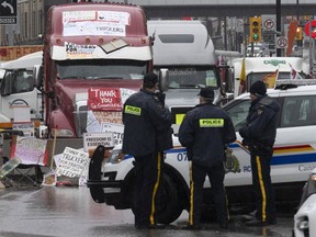 Police officers keep an eye on protest trucks, in Ottawa
