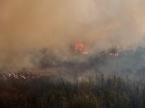 Wildfires have forced thousands out of several communities in Western Canada. A wildfire burns near Flin Flon, Man., as seen from a helicopter surveying the situation, Tuesday, May 14, 2024.