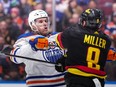 Edmonton Oilers' Connor McDavid, back left, checks Vancouver Canucks' J.T. Miller during the third period of an NHL hockey game in Vancouver, on Monday, November 6, 2023.